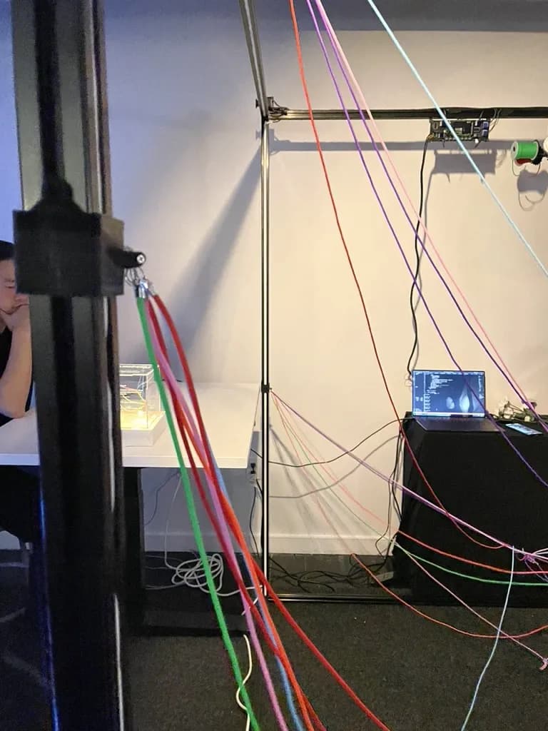 View from inside the installation showing cascading threads, the acrylic model, and the control system