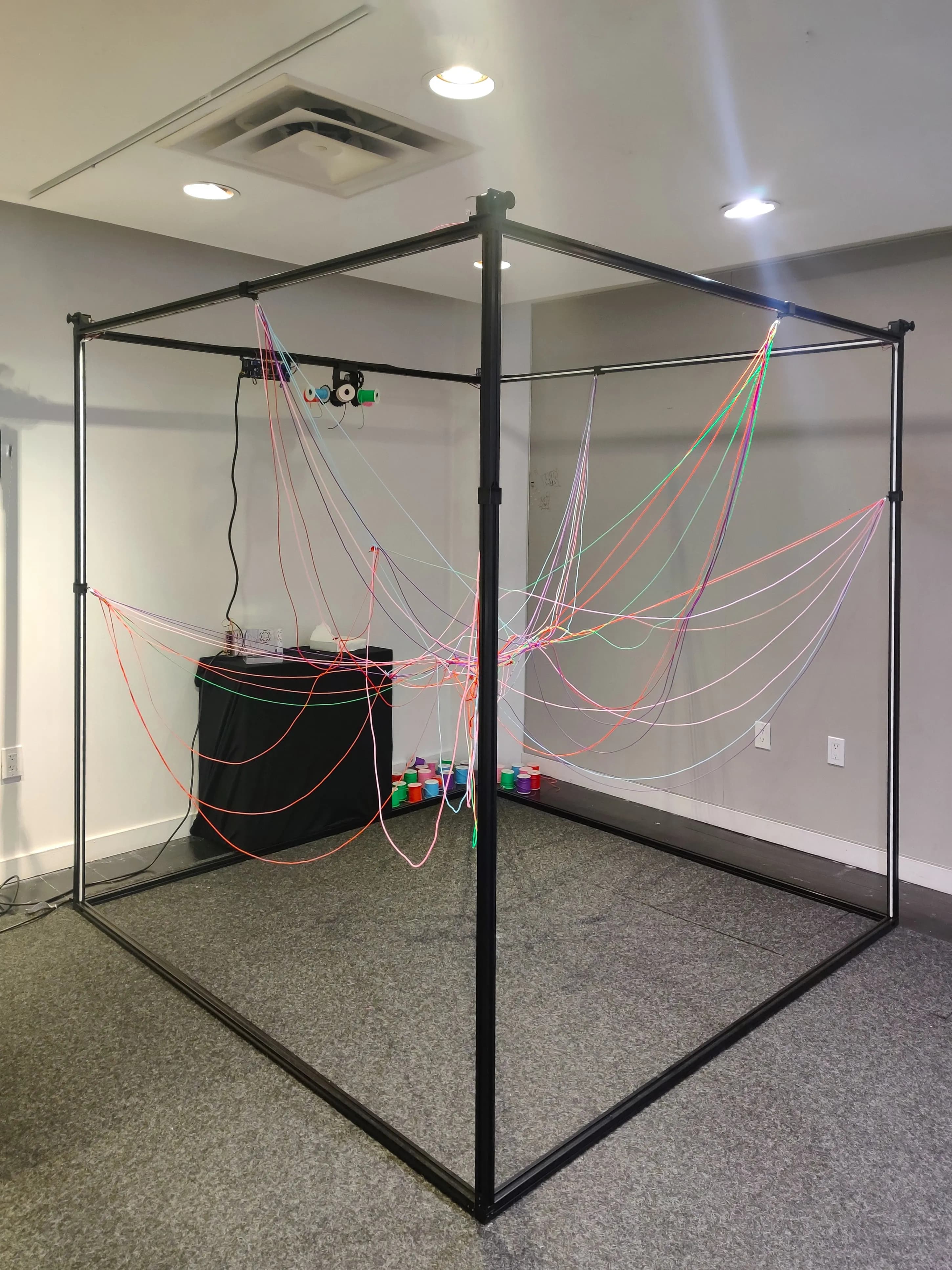 The metal cube frame after the first performance, threads accumulated from hours of conversation