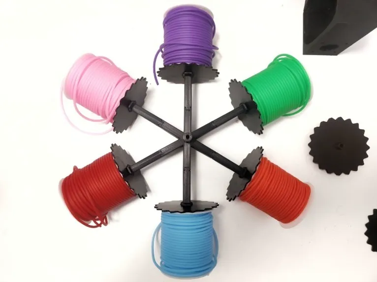 Six colored thread spools arranged in a 3D-printed holder, viewed from above
